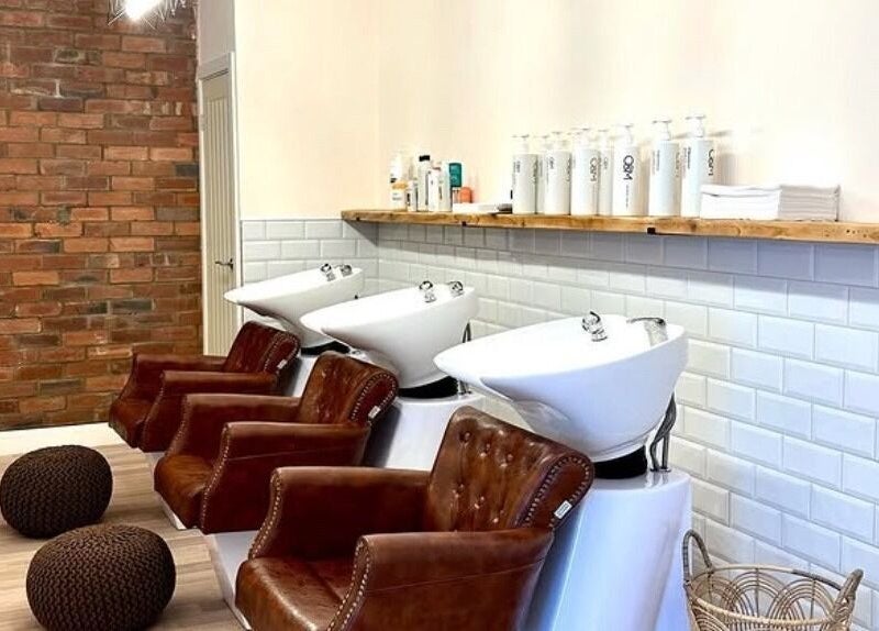 Chic hair wash area at Omor Studio, Wetherby, England, GB with modern sinks and plush chairs.