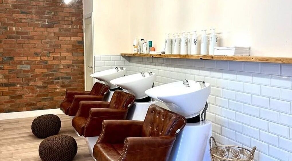 Chic hair wash area at Omor Studio, Wetherby, England, GB with modern sinks and plush chairs.