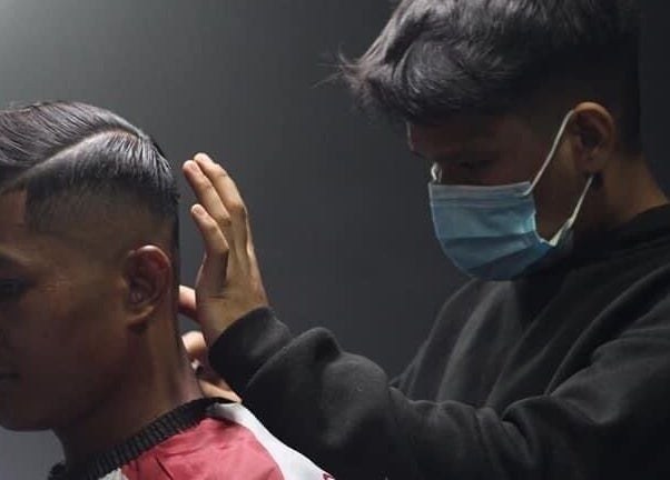 Barber styling a client's hair at Blues Barbershop, Sungai Buloh, Selangor, MY. Modern grooming services in action.