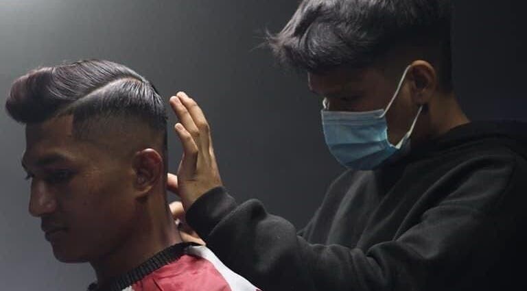 Barber styling a client's hair at Blues Barbershop, Sungai Buloh, Selangor, MY. Modern grooming services in action.