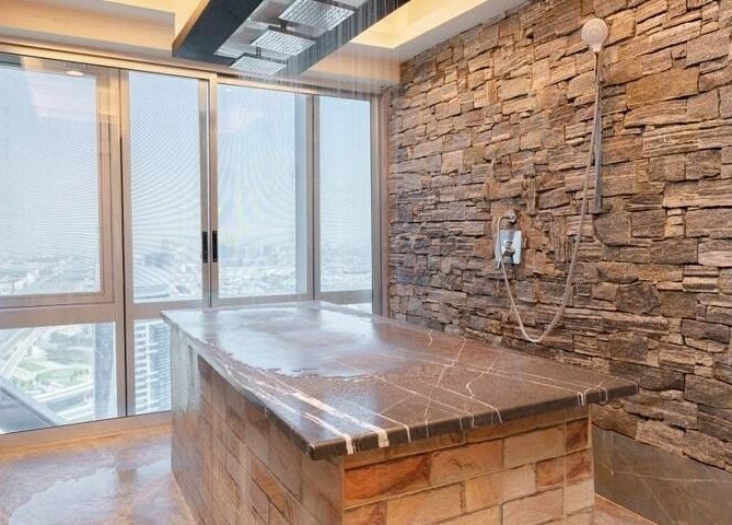 Luxurious stone spa room at Effect Spa, Dubai, Dubai, AE, featuring rain shower and city view.