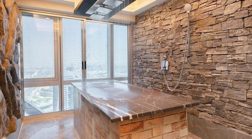 Luxurious stone spa room at Effect Spa, Dubai, Dubai, AE, featuring rain shower and city view.
