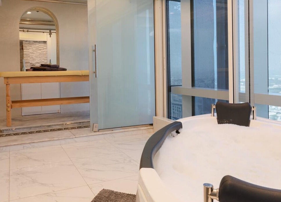 Luxurious spa room with city view at Effect Spa, Dubai, Dubai, AE, featuring a marble floor and plush bathtub.