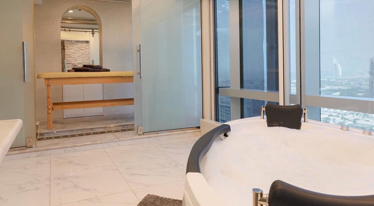 Luxurious spa room with city view at Effect Spa, Dubai, Dubai, AE, featuring a marble floor and plush bathtub.