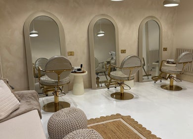 Elegant salon interior at Vanity, Stoke-on-Trent, England, GB with plush chairs and arched mirrors.