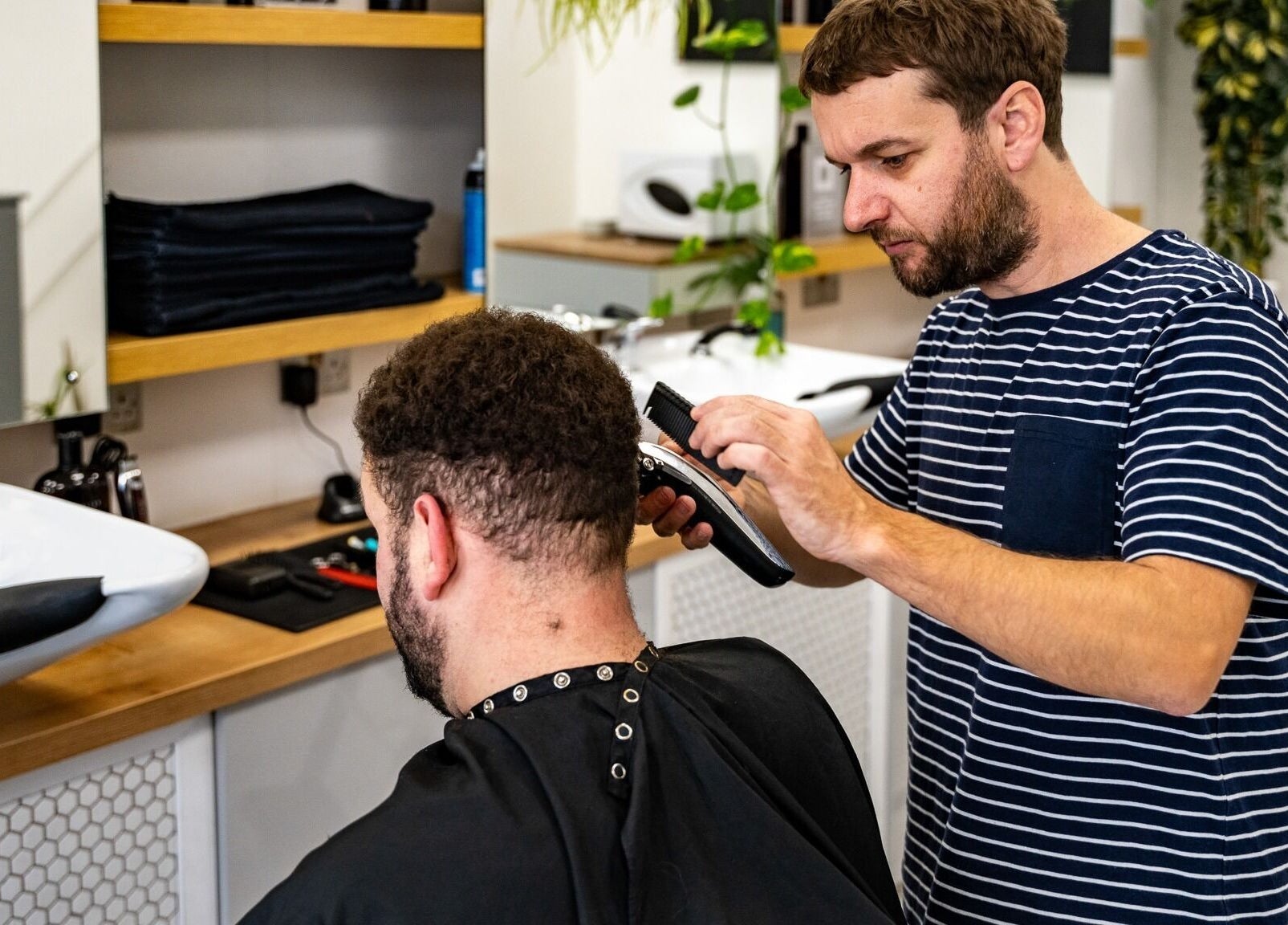 Barber styling a client's hair at Yallop, London, England, GB. Professional grooming service.
