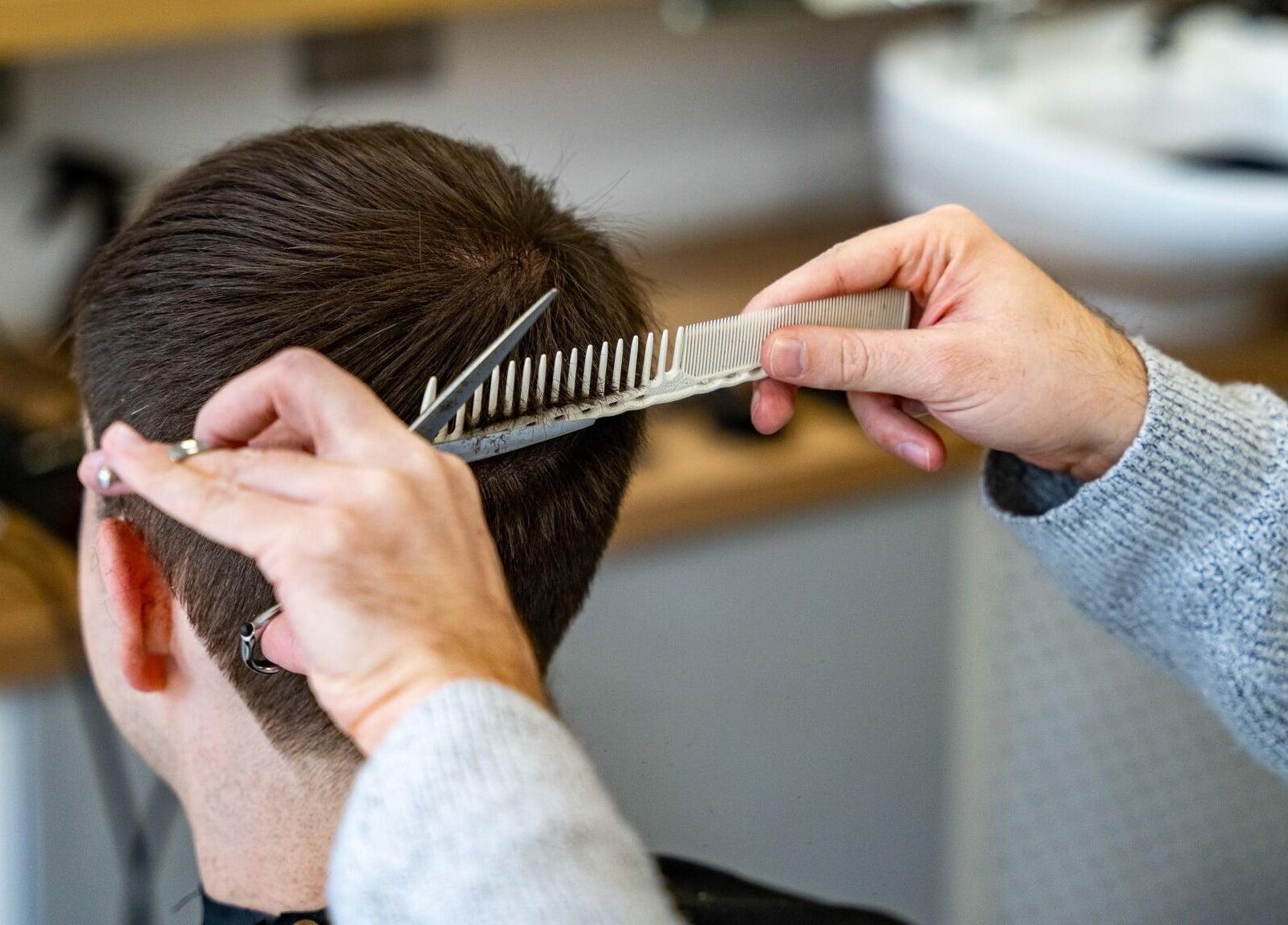A stylist expertly trims a client's hair at Yallop, London, England, GB.