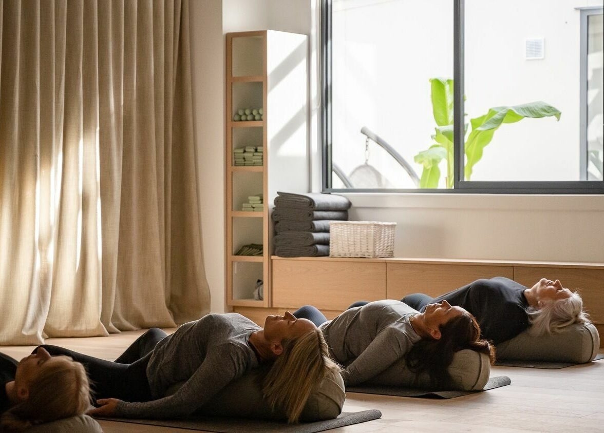 Relaxing yoga session at Well and Being, Dunedin, Otago, NZ with participants resting peacefully.
