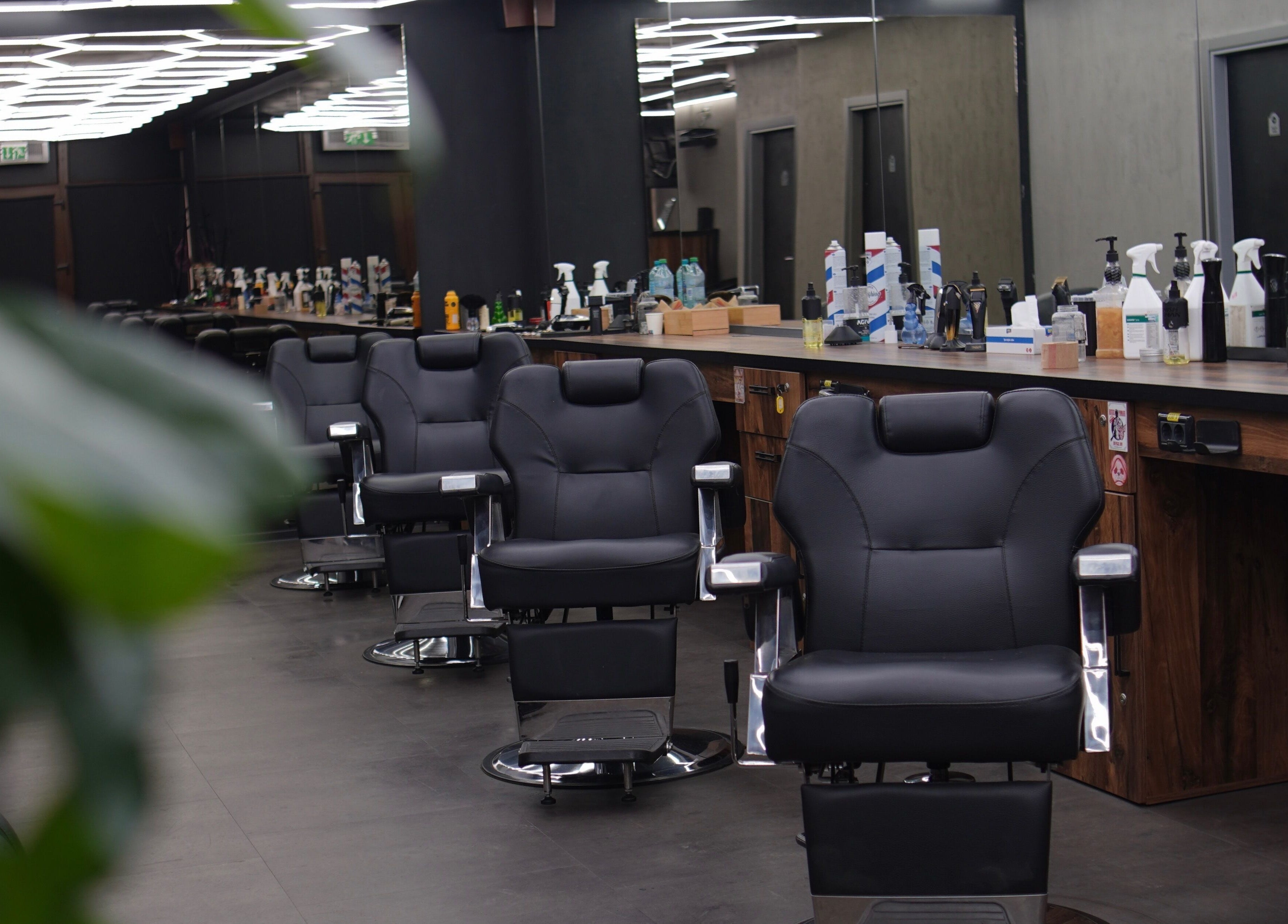 Interior modern al FADE FACTORY POPESTI, Popești-leordeni, România, cu scaune de frizerie negre și elegante.