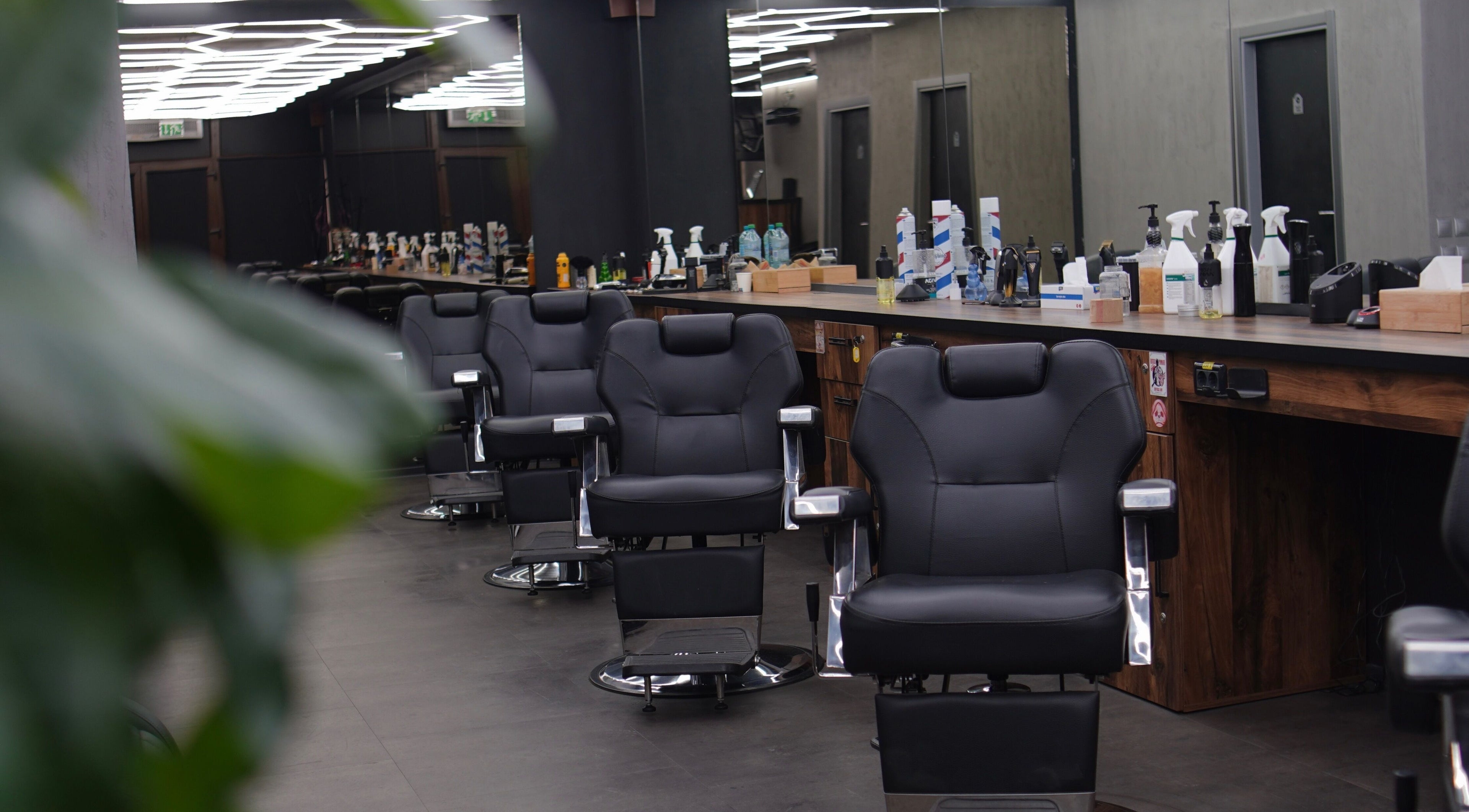 Interior modern al FADE FACTORY POPESTI, Popești-leordeni, România, cu scaune de frizerie negre și elegante.