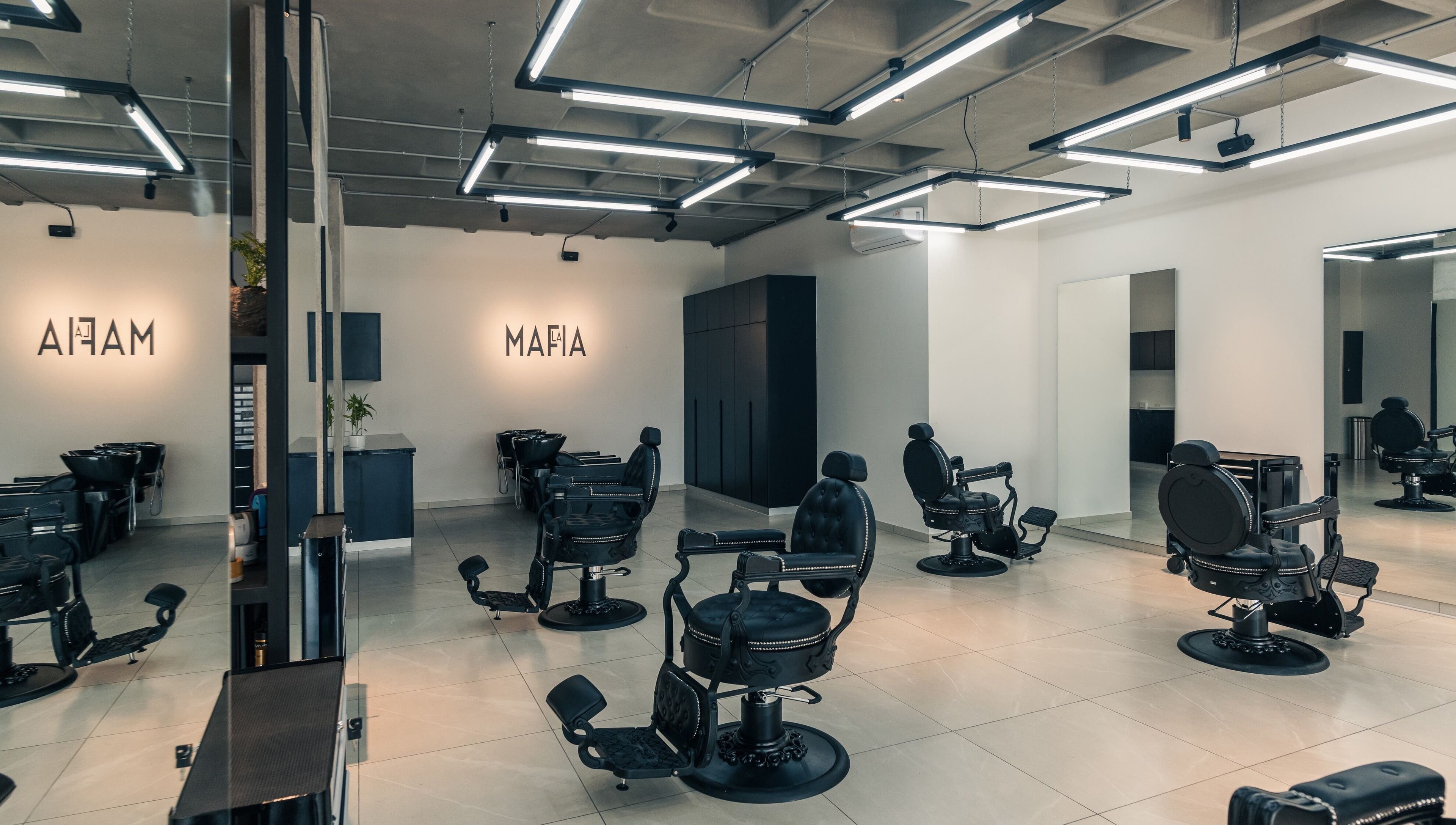 Interior moderno de LA MAFIA - LOS CUSIS en Santa Cruz De La Sierra, BO, con sillas de peluquería negras.