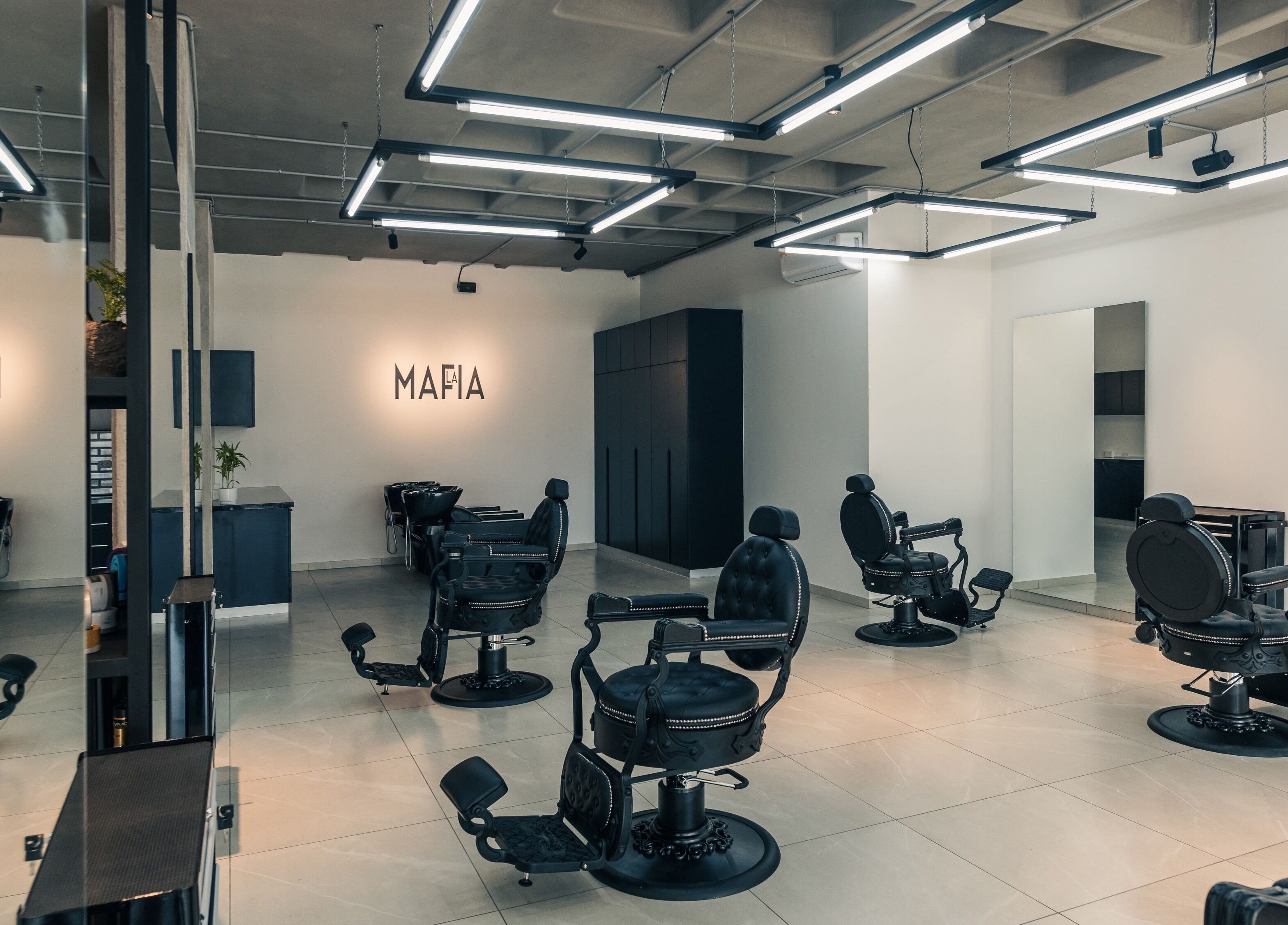 Interior moderno de LA MAFIA - LOS CUSIS en Santa Cruz De La Sierra, BO, con sillas de peluquería negras.