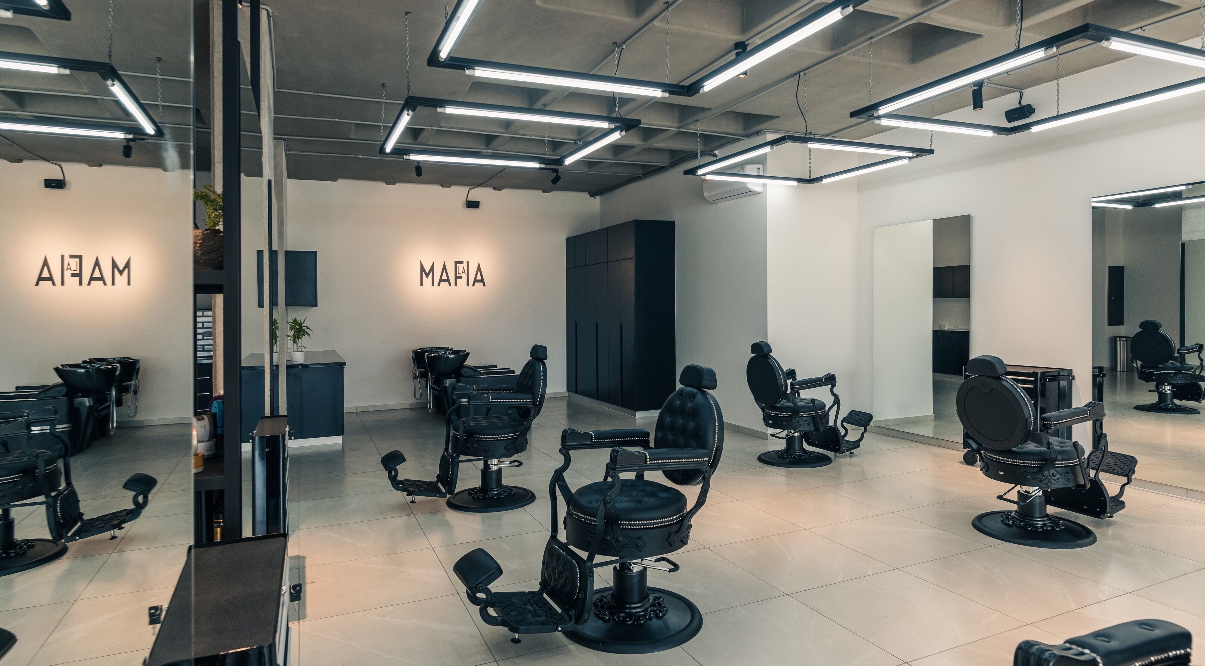 Interior moderno de LA MAFIA - LOS CUSIS en Santa Cruz De La Sierra, BO, con sillas de peluquería negras.