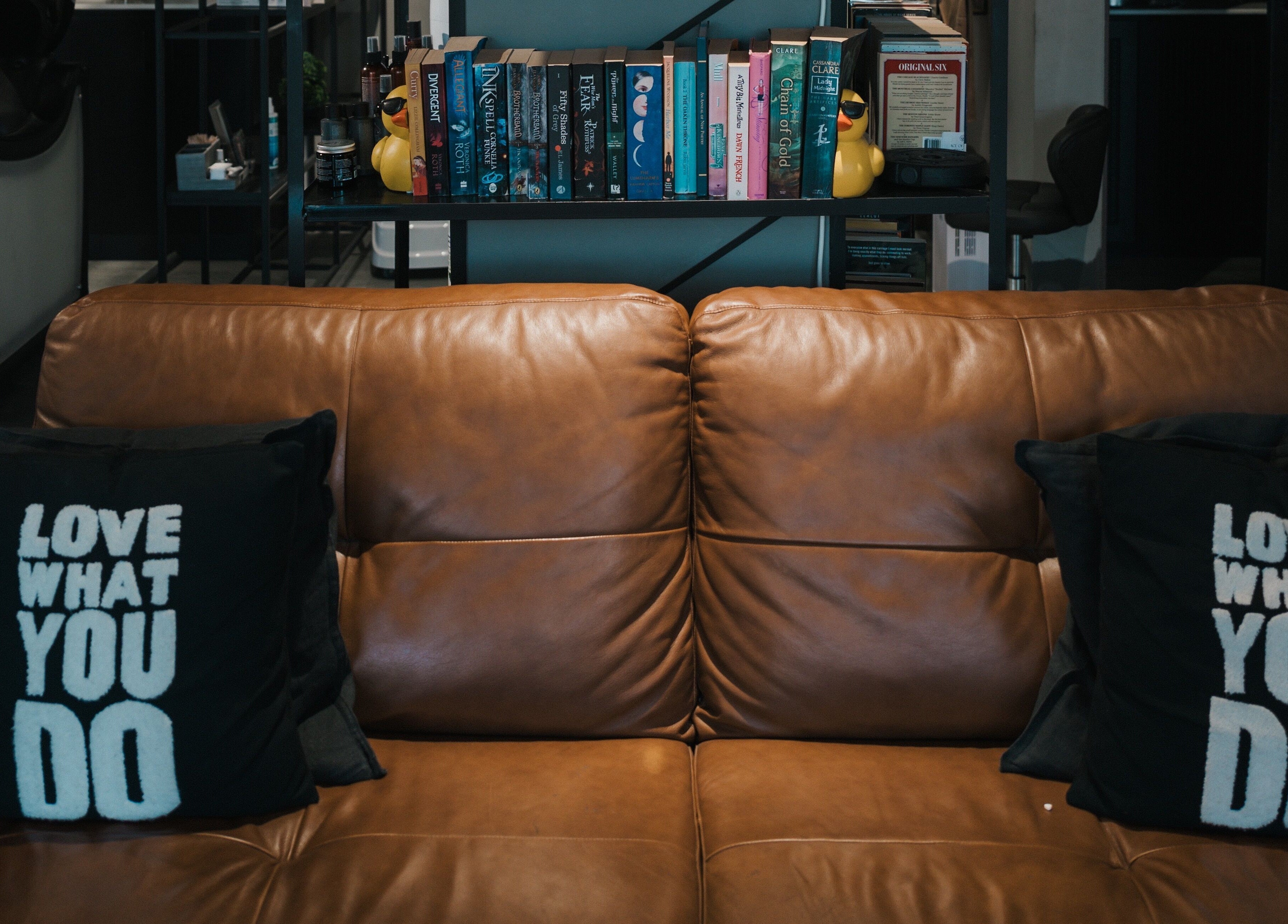 Comfortable brown leather couch with motivational pillows at Ace of Fades Mens Salon, أبو ظبي, أبو ظبي, AE.