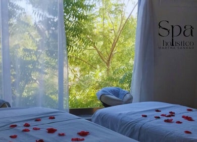 Sala de masaje con pétalos rojos en Spa Holistico Martha Sankar, Manzanillo, MX, con vista a la naturaleza.
