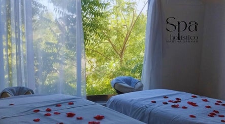 Sala de masaje con pétalos rojos en Spa Holistico Martha Sankar, Manzanillo, MX, con vista a la naturaleza.