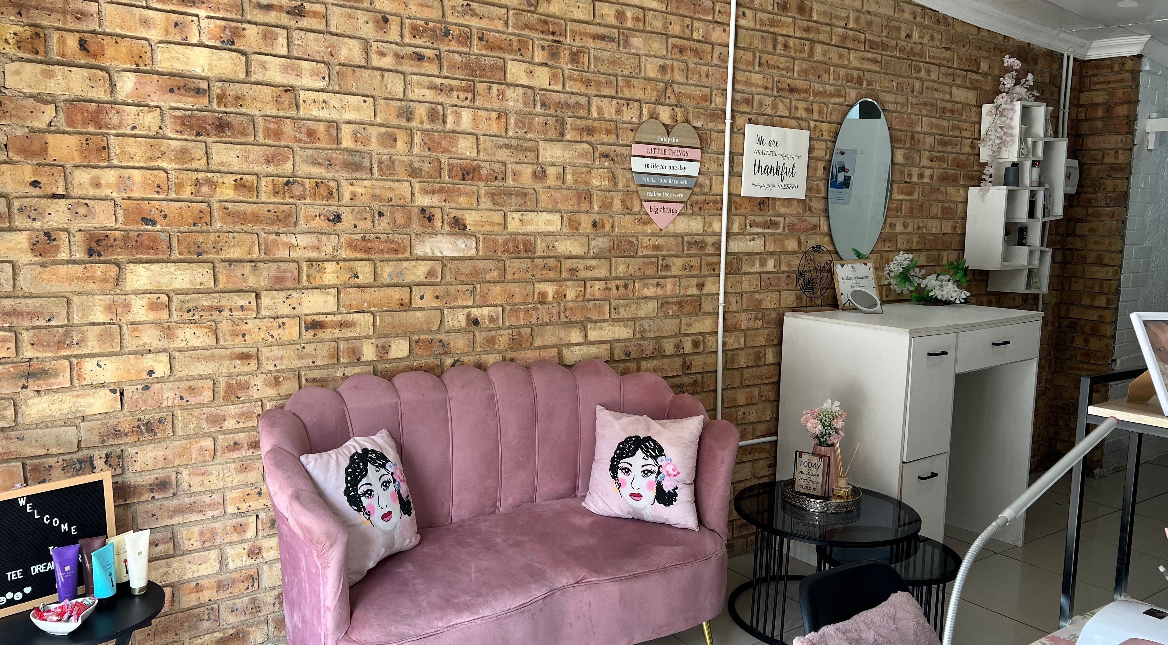 Chic interior of Tee Dream Parlour in Alberton, Gauteng, ZA featuring a pink velvet sofa against a brick wall.