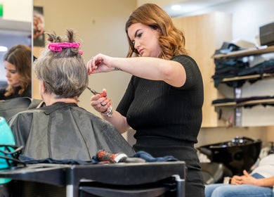 Stylist at Booval - Gaye's Hair Fashions, Booval, Queensland, AU, expertly cuts a client's hair.