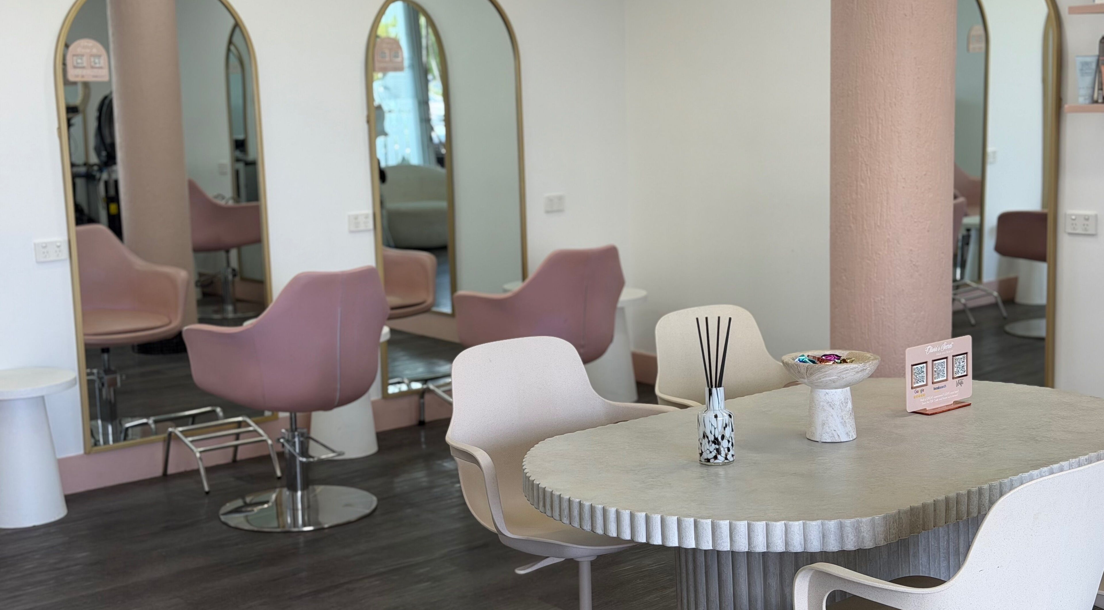 Elegant interior of Olivia's Secret Hair and Beauty in Buddina, Queensland, AU featuring chic pink chairs and mirrors.