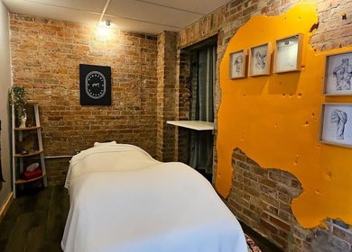 Cozy massage room in Mindful Massage, Pembroke, Ontario with exposed brick and vibrant art.
