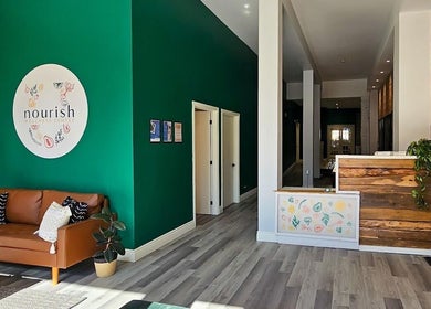 Warm and inviting lobby of Mindful Massage, Pembroke, Ontario, CA featuring a green accent wall and comfortable seating.