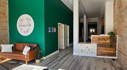 Warm and inviting lobby of Mindful Massage, Pembroke, Ontario, CA featuring a green accent wall and comfortable seating.