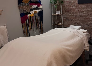 Relaxing massage table setup at Mindful Massage, Pembroke, Ontario, CA, with a calming decor and woven tapestry.