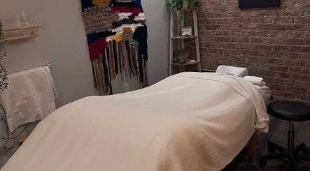 Relaxing massage table setup at Mindful Massage, Pembroke, Ontario, CA, with a calming decor and woven tapestry.