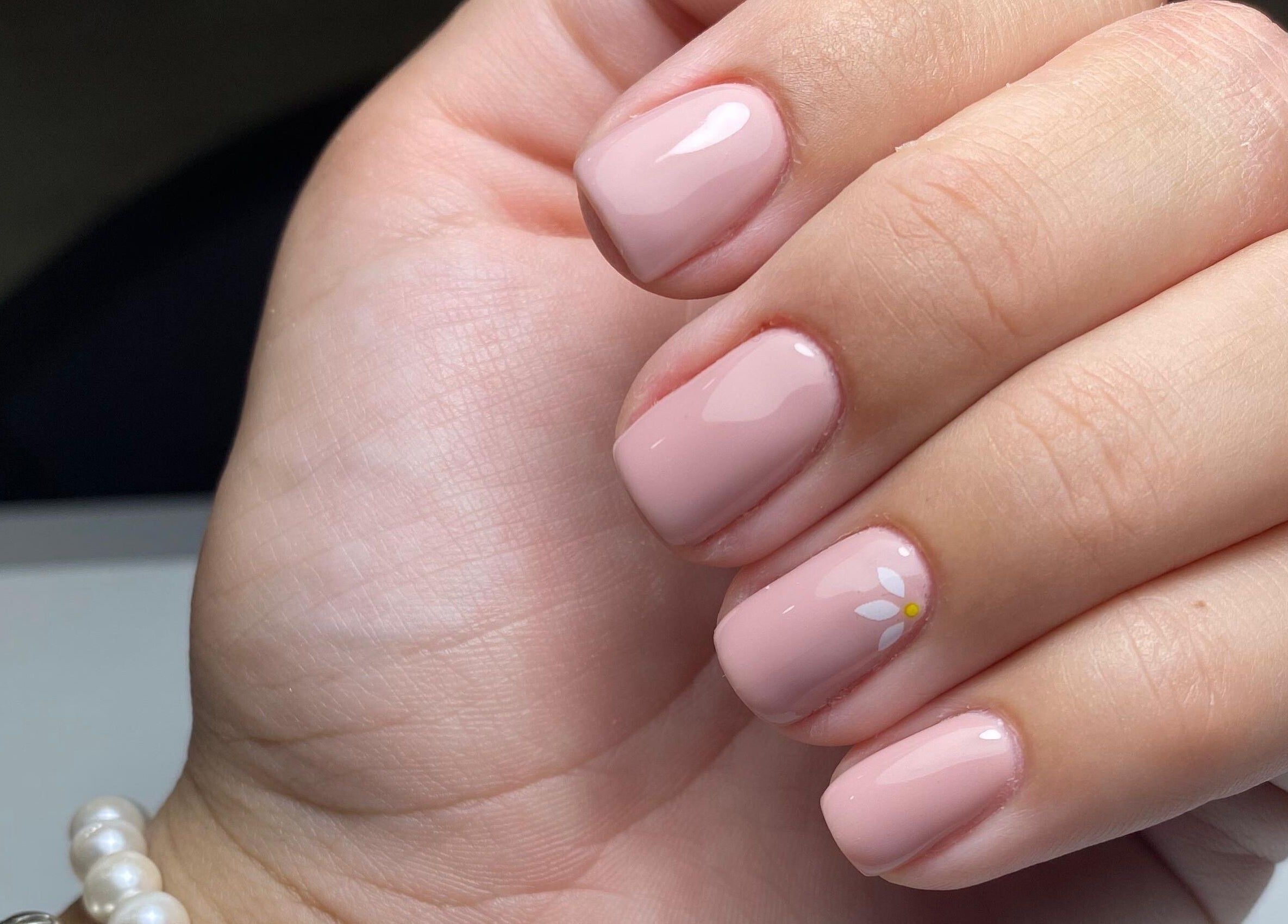 Unhas com esmalte nude e flor decorativa no La Bellezza Studio, Algés, Lisboa, PT.