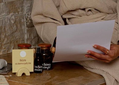 Guest reading at Le Senes Spa, Riyadh with relaxing spa items nearby on a stone bench.