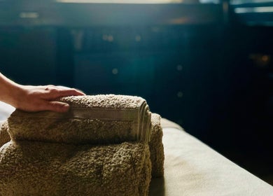 Hand resting on soft towels at Purl Massage Therapy, Glasgow, Scotland, GB, evoking relaxation and warmth.