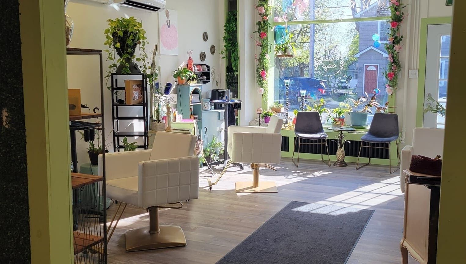 Bright salon interior at Practically Magic, South Glens Falls, New York, US with modern chairs and plants.