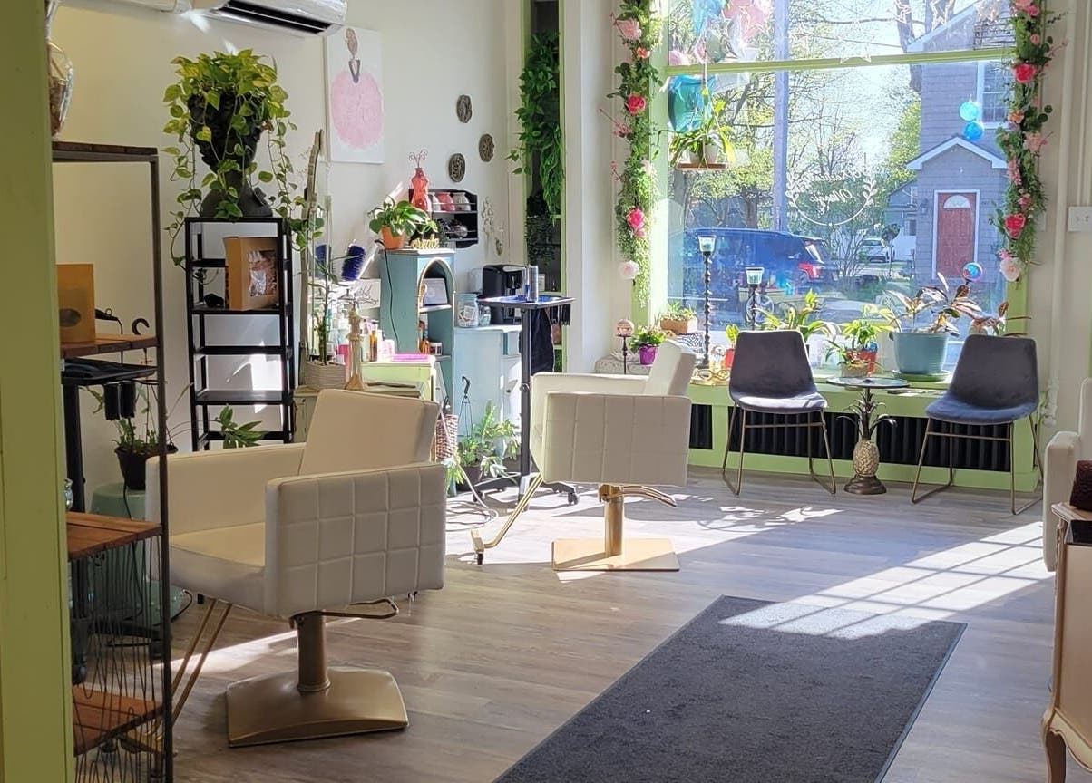 Bright salon interior at Practically Magic, South Glens Falls, New York, US with modern chairs and plants.