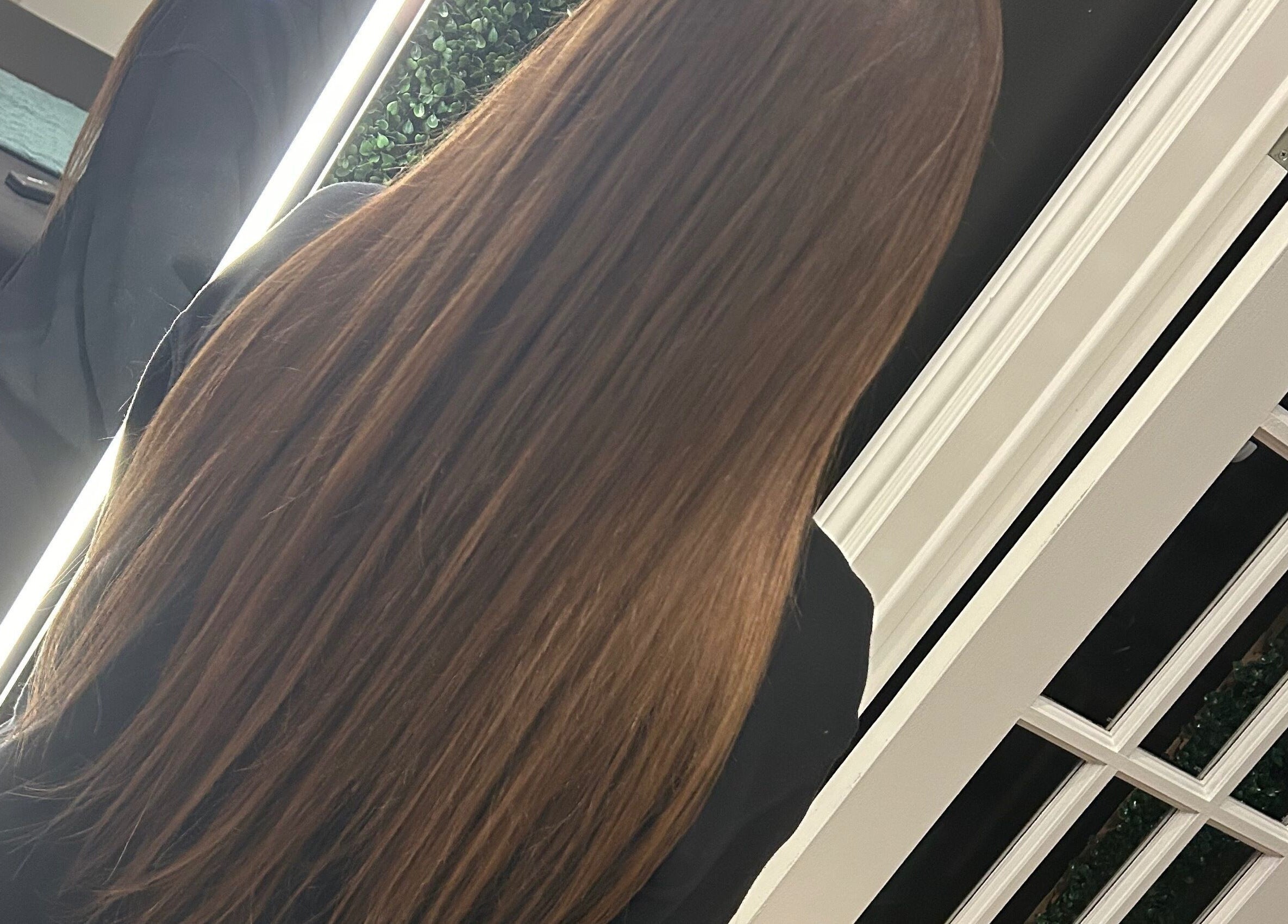 Long, sleek hair in a mirror reflection at Amour Esthetics LDN, London, Ontario, CA.