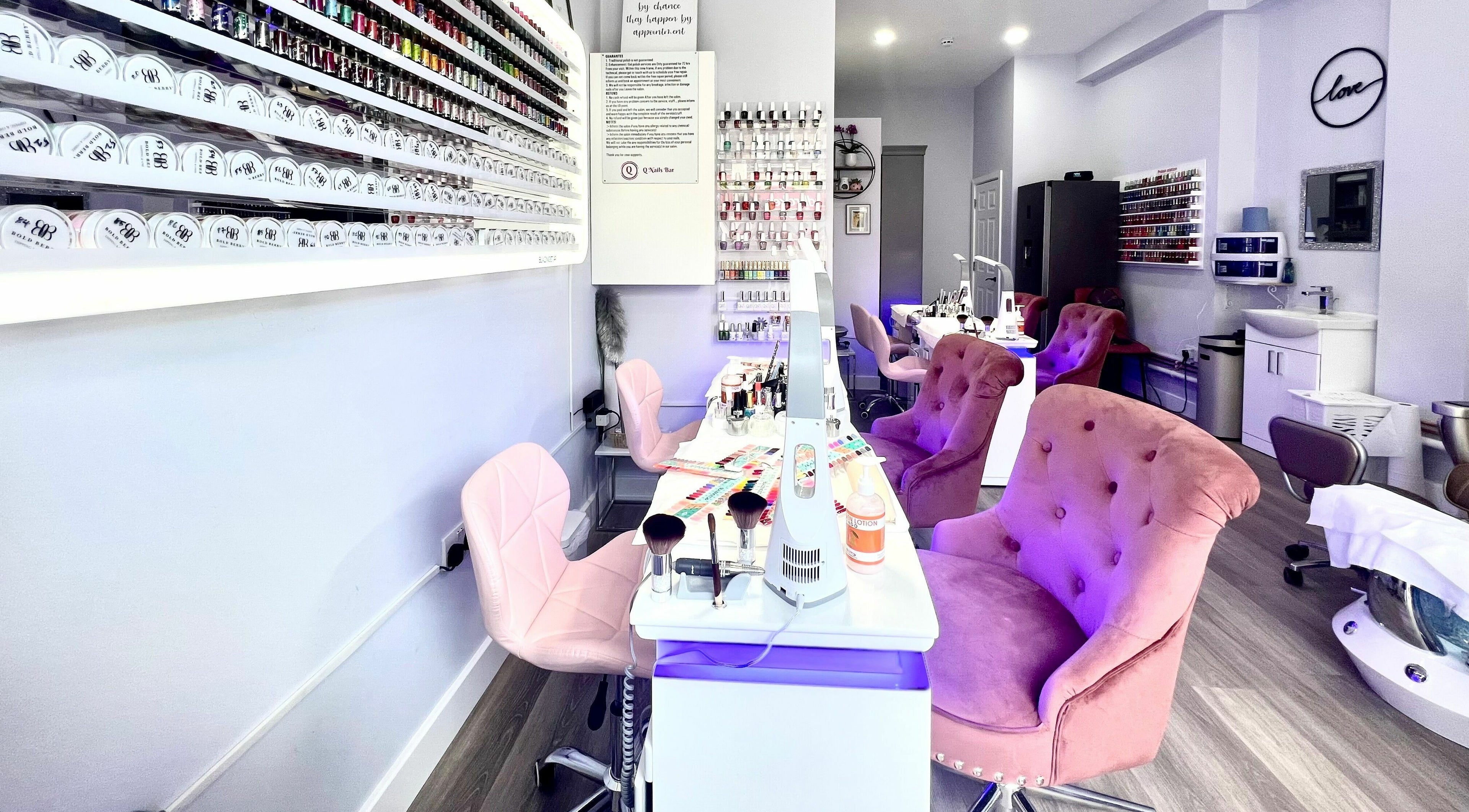 Modern interior of Q Nail Bar in London, England, GB, featuring plush chairs and a variety of nail polishes.