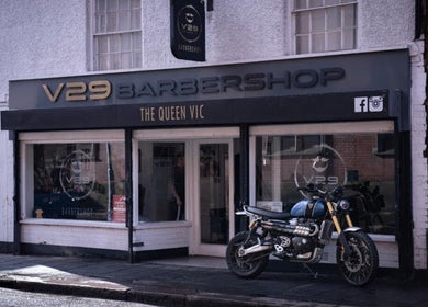 V29 Barbershop exterior in Burton Upon Trent, England, showcasing modern design with a motorcycle parked outside.