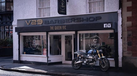 V29 Barbershop exterior in Burton Upon Trent, England, showcasing modern design with a motorcycle parked outside.