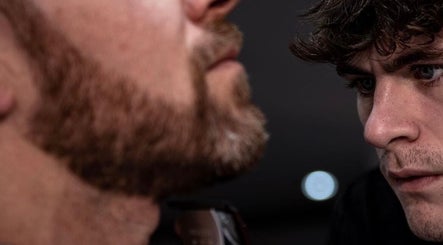 Barber at V29 Barbershop, Burton Upon Trent, England, shaping a client's beard with precision.