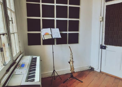 Estudio musical en Pranadis Studio, Valparaíso, con un piano, saxofón y paneles acústicos.