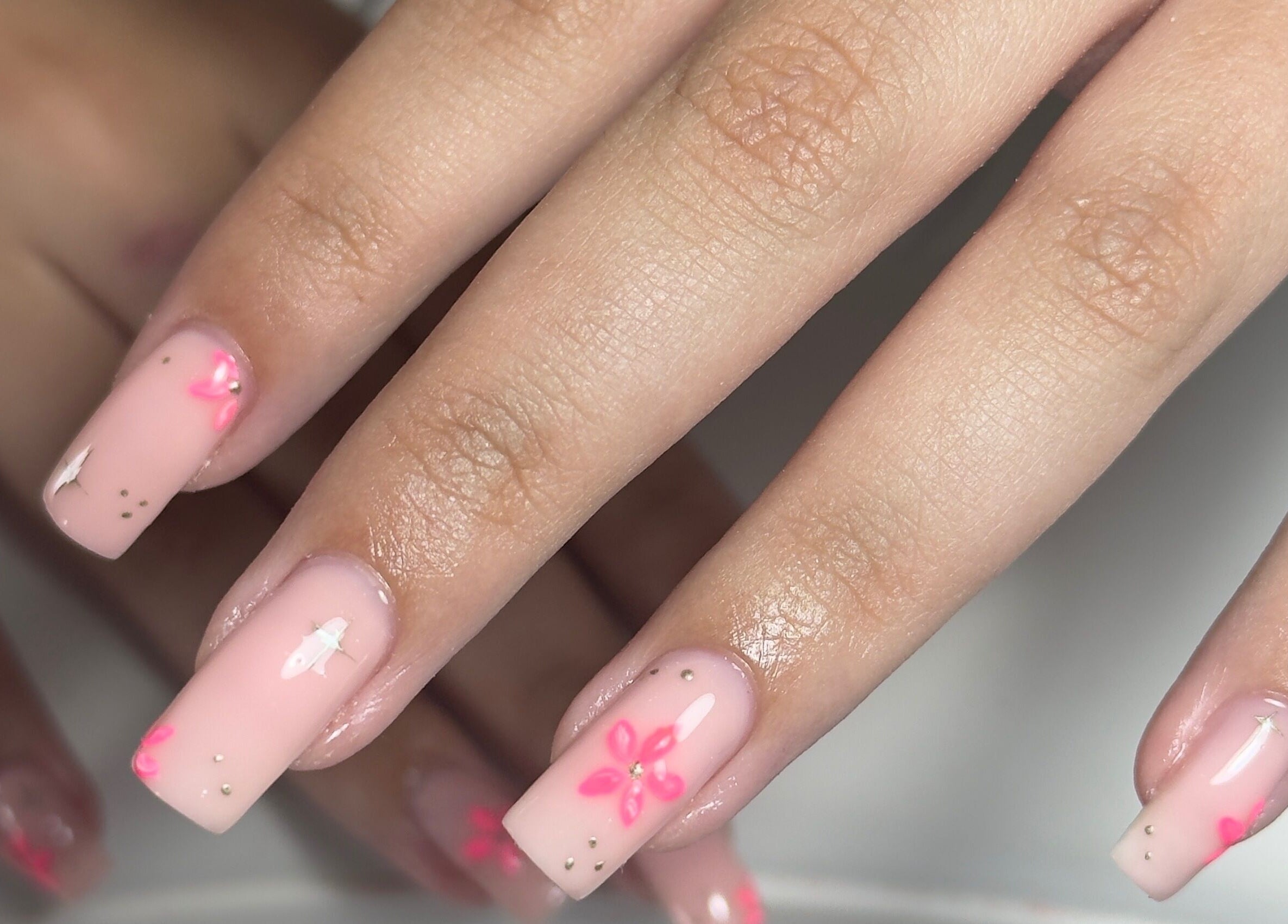 Elegant floral nail art on soft pink nails at Toni’s Beauty Lounge, Towcester, England, GB.