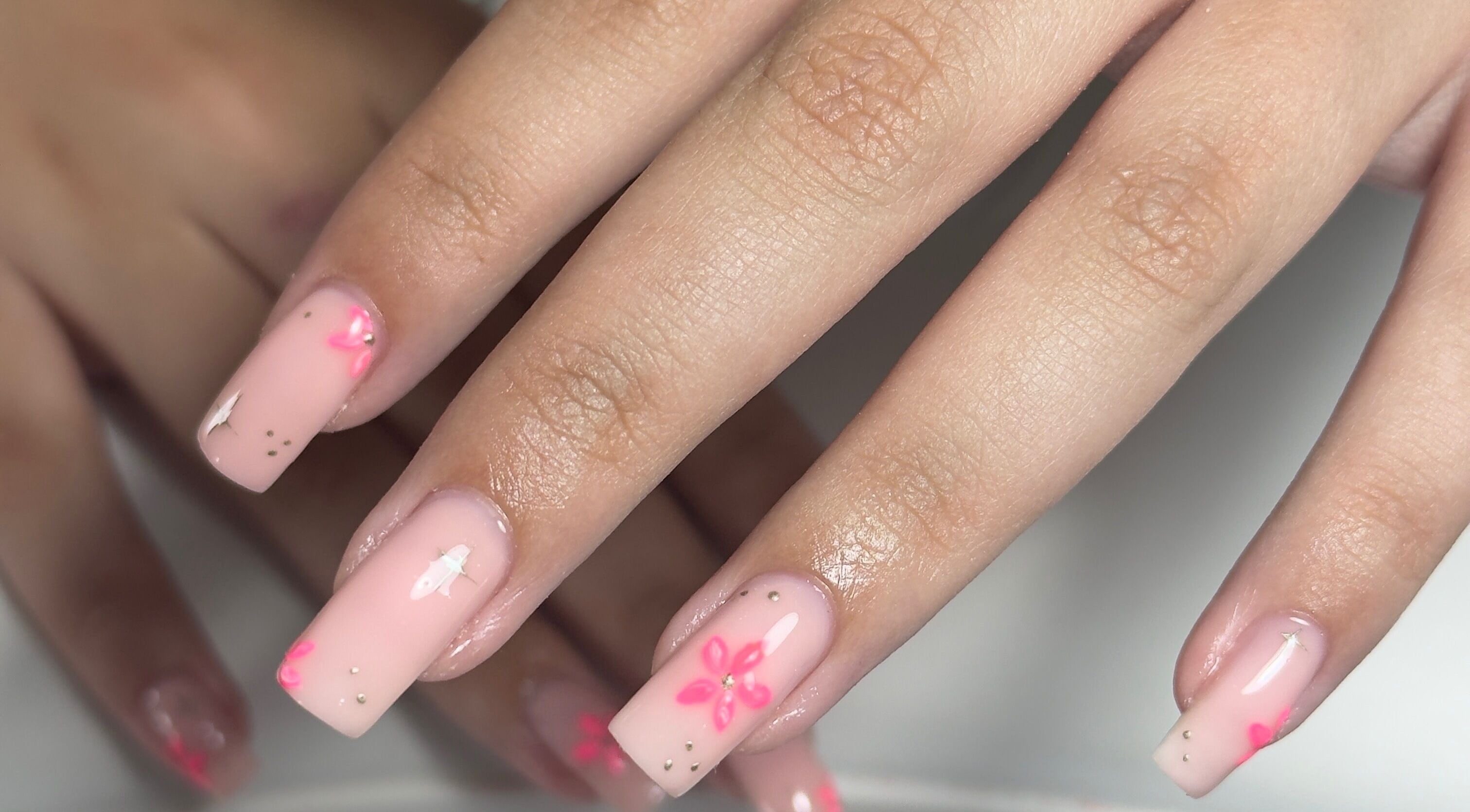 Elegant floral nail art on soft pink nails at Toni’s Beauty Lounge, Towcester, England, GB.