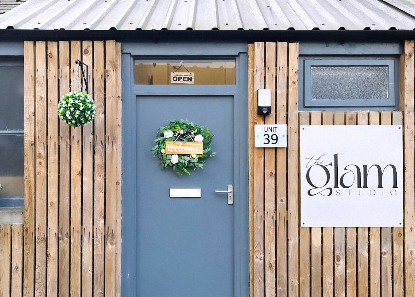 Entrance of The Glam Studio in Farsley, Leeds, England, GB, featuring a wood facade and decorative wreath.