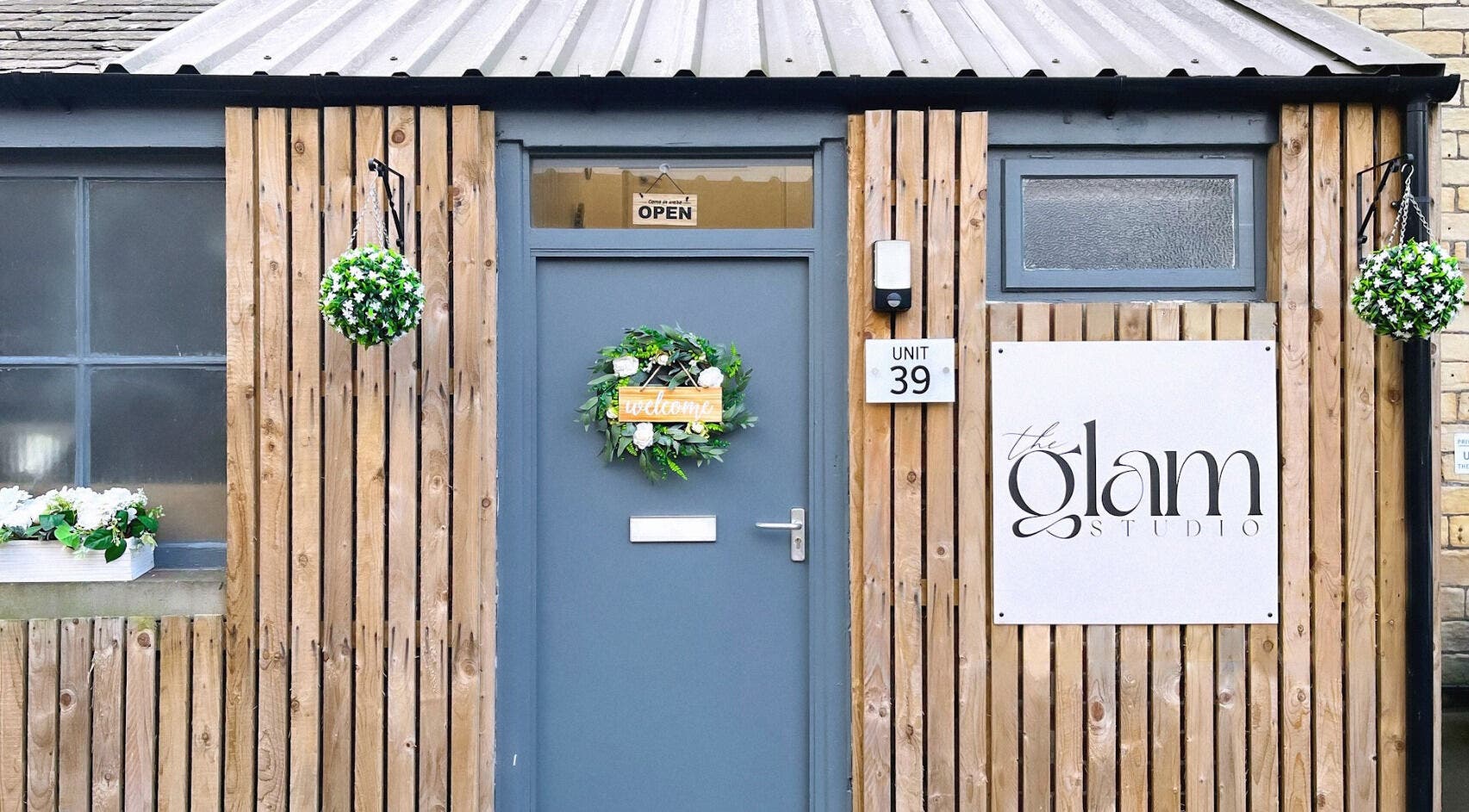 Entrance of The Glam Studio in Farsley, Leeds, England, GB, featuring a wood facade and decorative wreath.