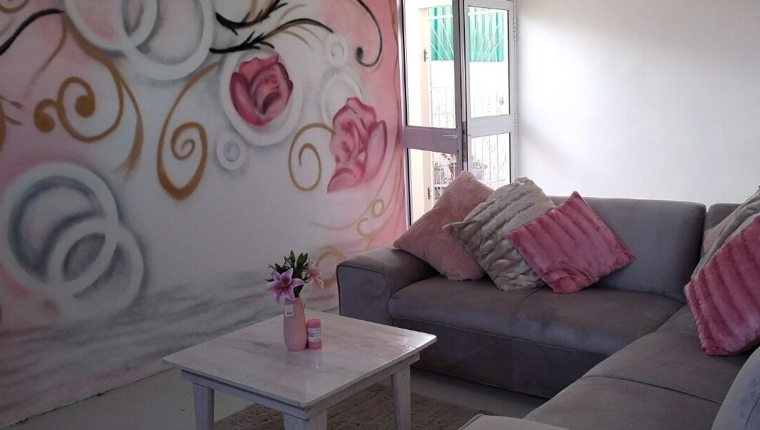 Cozy seating with floral art at Just Relax, Gqeberha, Eastern Cape, ZA. Soft pink and gray decor.