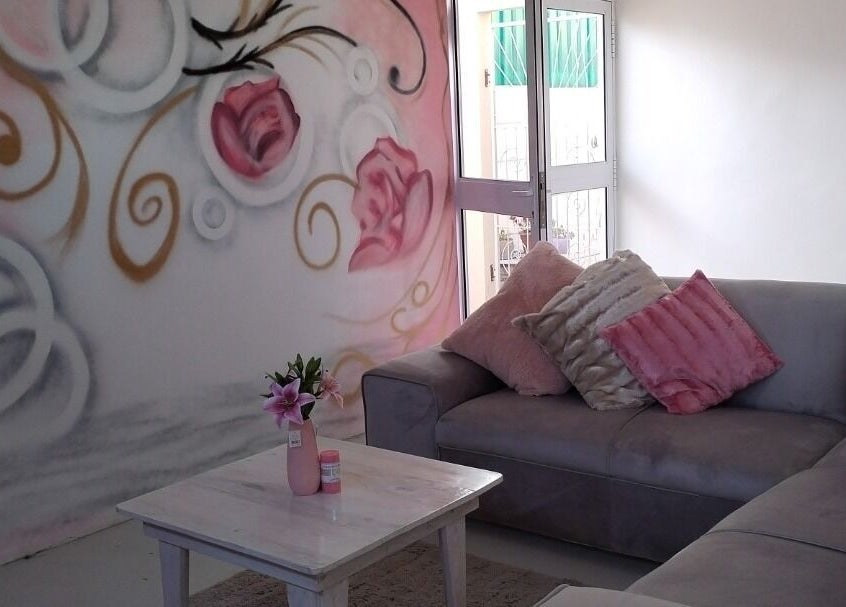 Cozy seating with floral art at Just Relax, Gqeberha, Eastern Cape, ZA. Soft pink and gray decor.