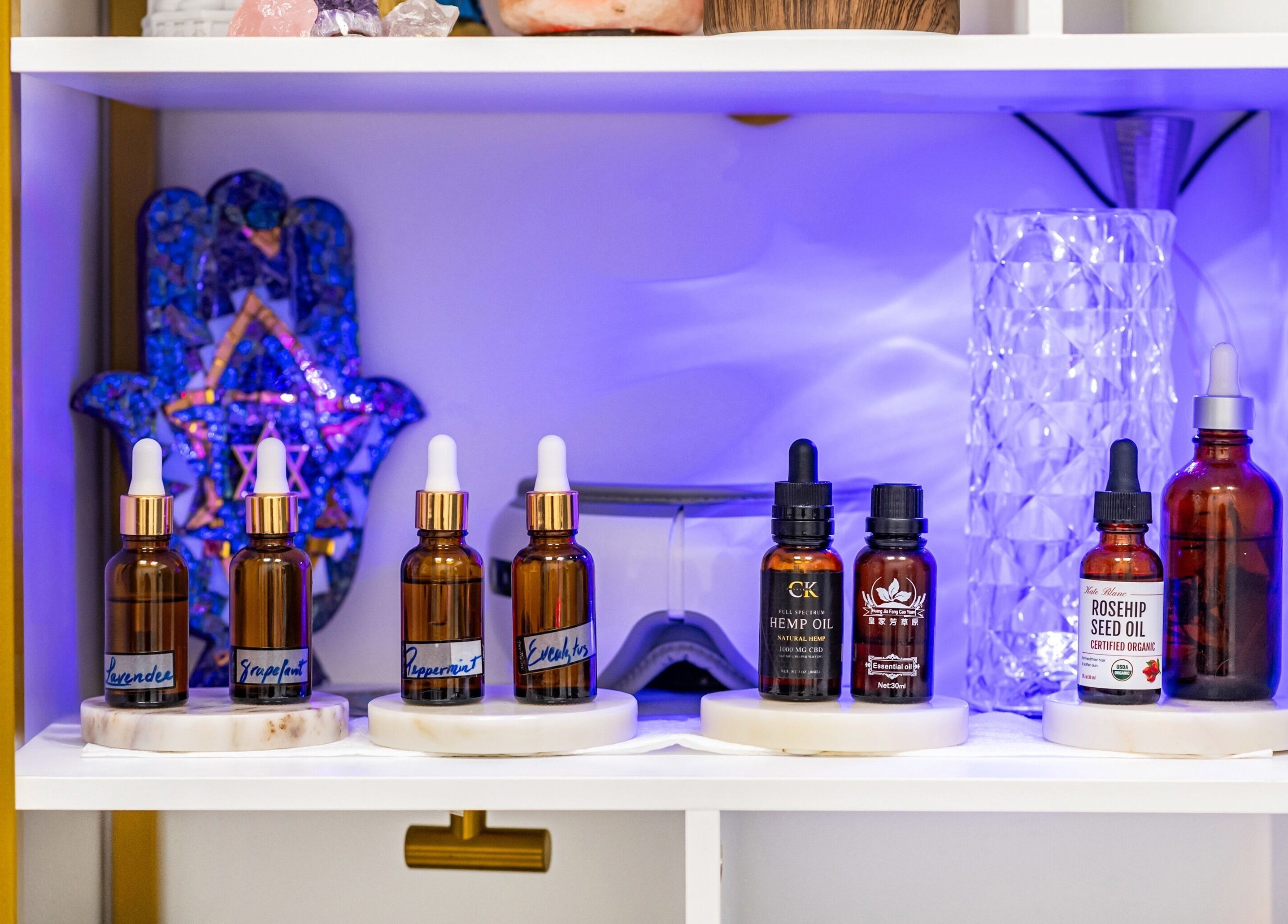 Essential oil collection at Marvella Bliss, Pembroke Pines, Florida, US, illuminated with tranquil blue light.