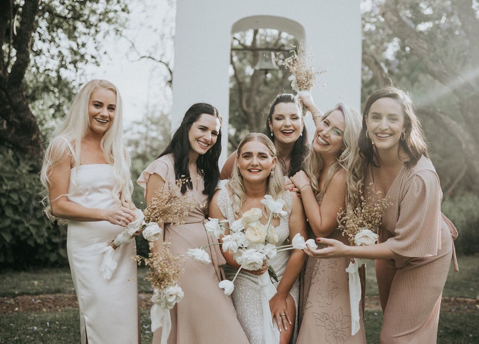 Bridal party at Makeup by Ameerah, Cape Town, Western Cape, ZA posing in elegant, pastel attire outdoors.