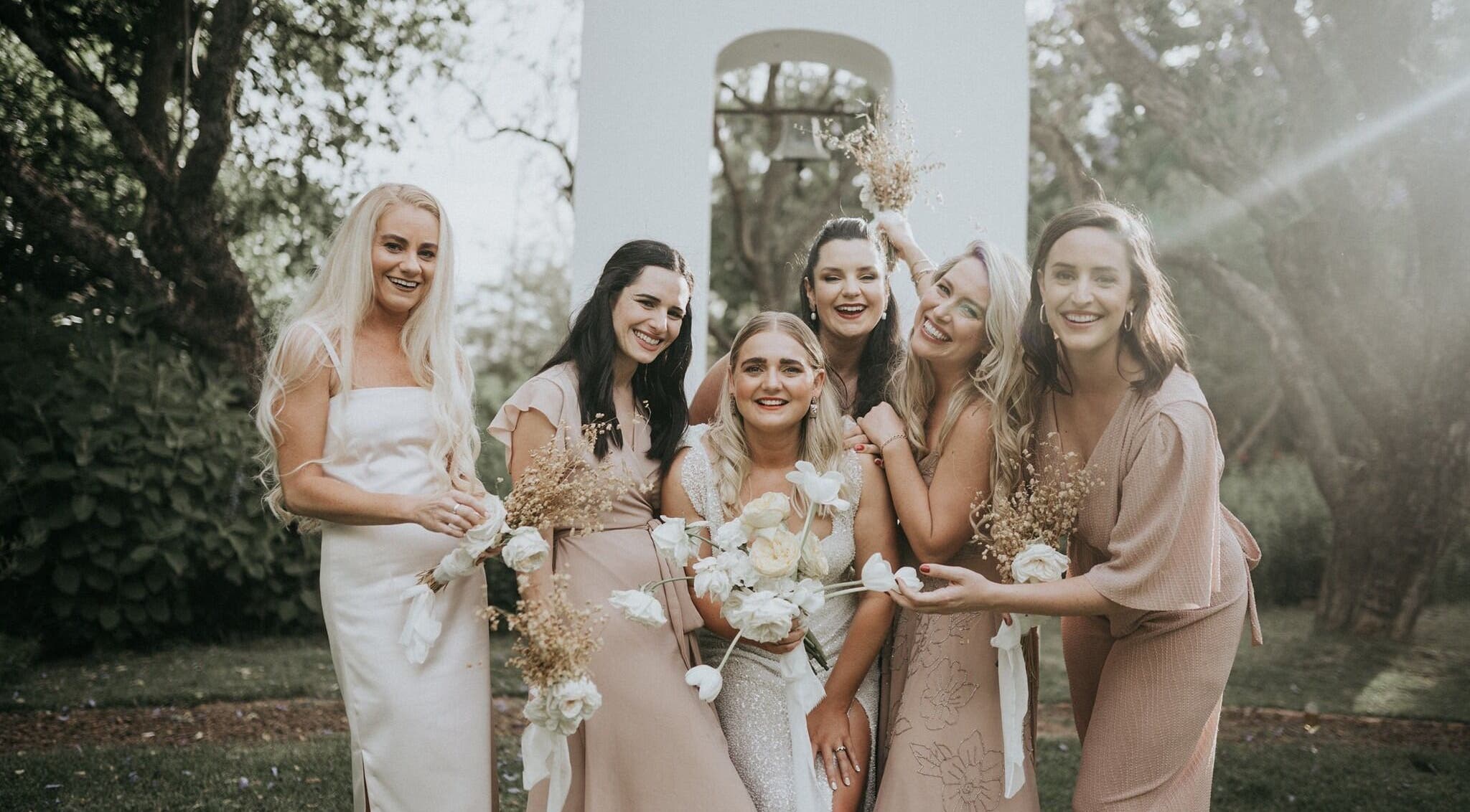 Bridal party at Makeup by Ameerah, Cape Town, Western Cape, ZA posing in elegant, pastel attire outdoors.