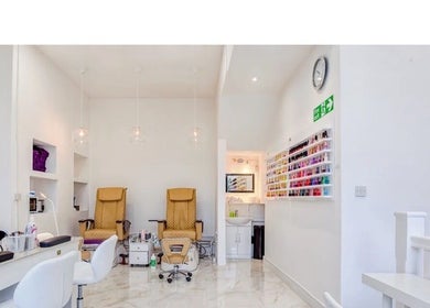 Interior of DK Nails Roehampton in London, England, GB featuring plush chairs and a nail polish display.