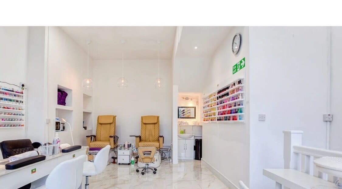 Interior of DK Nails Roehampton in London, England, GB featuring plush chairs and a nail polish display.